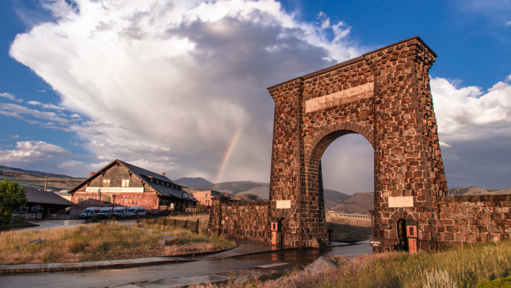 A rainbow appears between the iconic Roosevelt Arch and Yellowstone Forever store in Gardiner, MT.