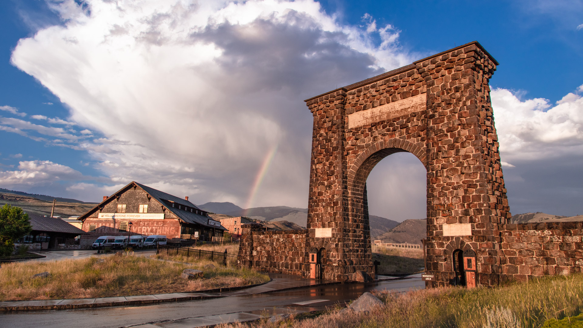 A rainbow appears between the iconic Roosevelt Arch and Yellowstone Forever store in Gardiner, MT.