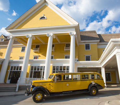 A historic yellowstone bus parked in front of Lake Yellowstone Hotel.